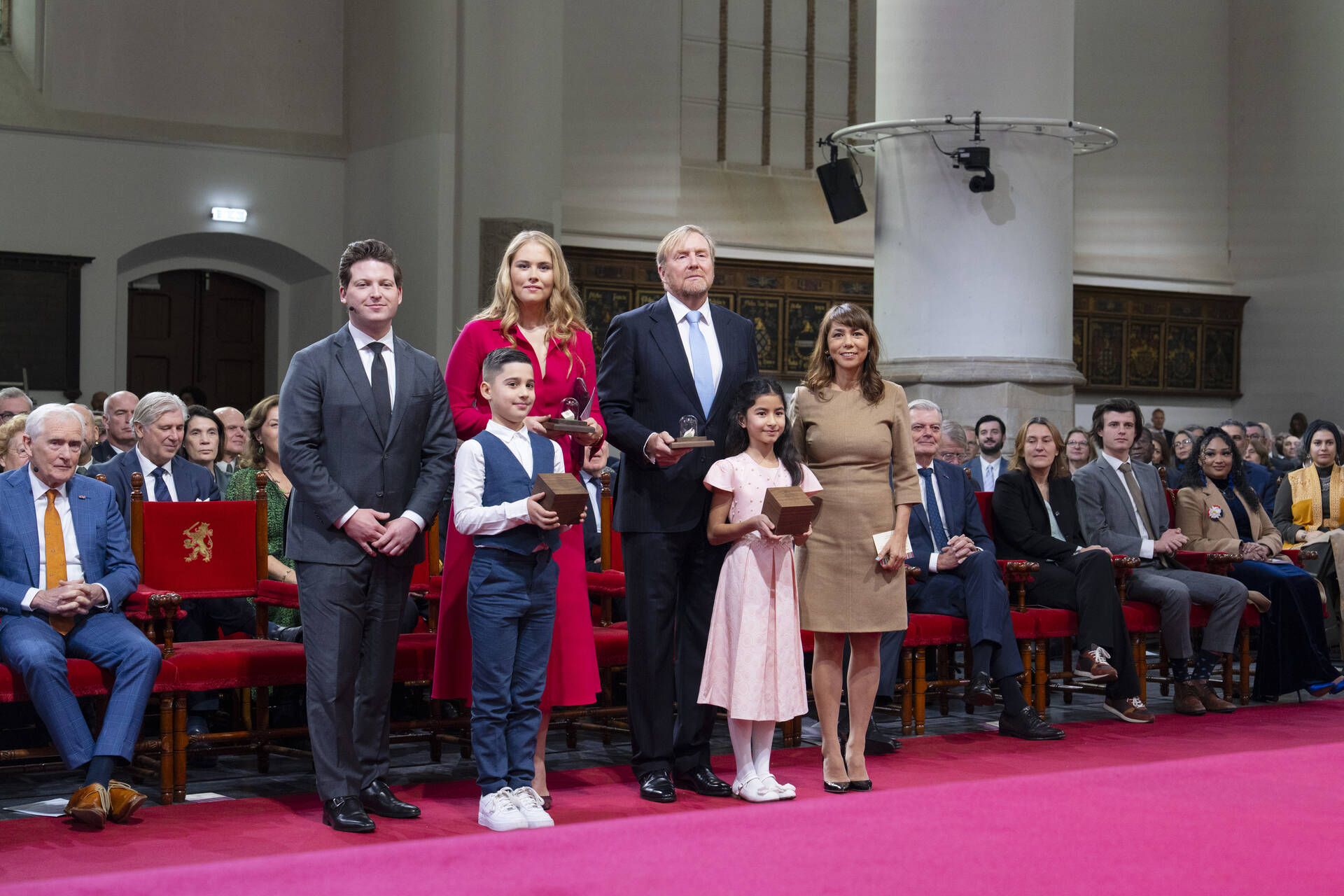 Koning en Prinses samen met de Kamervoorzitters nadat ze de miniatuur-Grondwet hebben gekregen uit handen van kinderen Owen (links) en Erkinay.